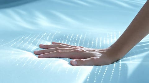 Hand pressing on a mattress surface.