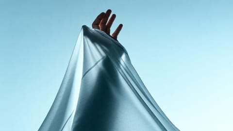 Hand lifting a sheet of soft fabric.
