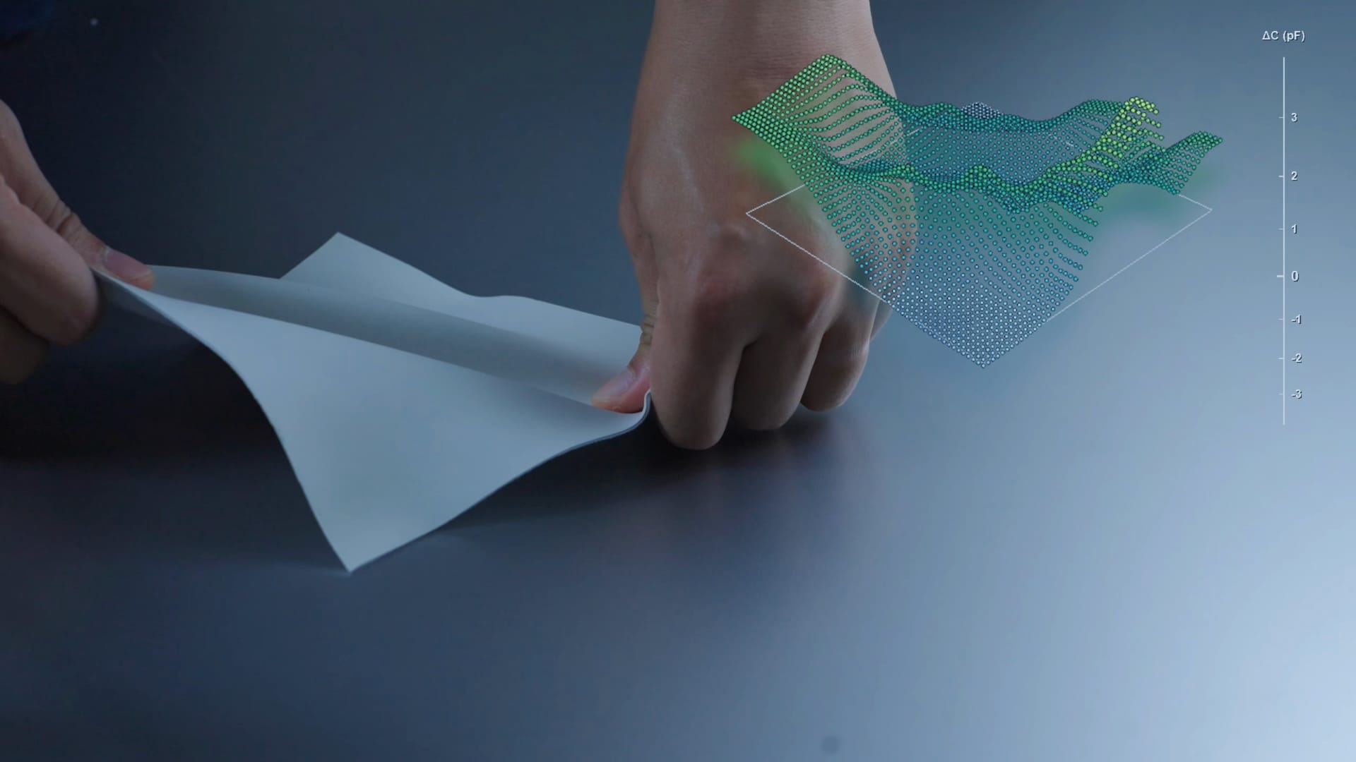 Hands stretching a thin flexible sheet, with a visualisation of the sensing data alongside.